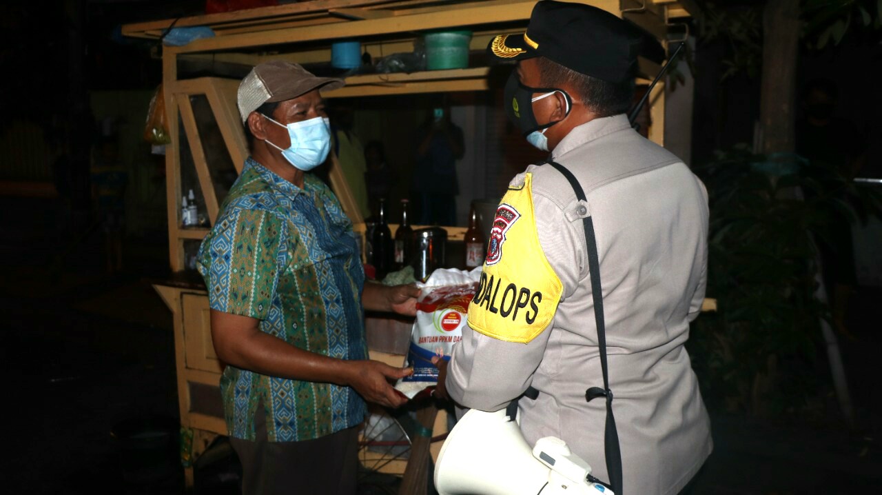 Petugas dari Polres Gresik sedang membagikan sembako kepada penjual makanan.