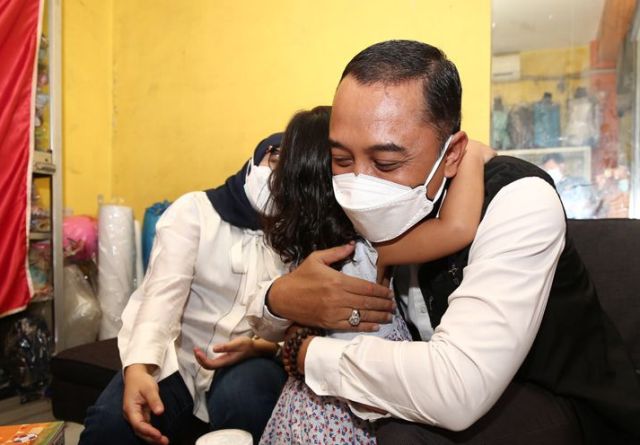 PELUK KASIH SAYANG: Wali Kota Surabaya, Eri Cahyadi didampingi istri memeluk salah seorang anak keluarga korban Covid-19. Foto/IST/Portalsurabaya.com