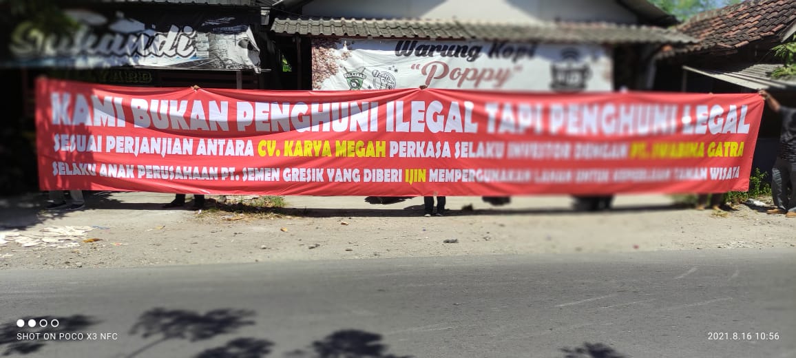Pedagang di Telaga Ngipik Gresik membeber spanduk protes rencana pembongkaran stand, Senin (16/8/2021).