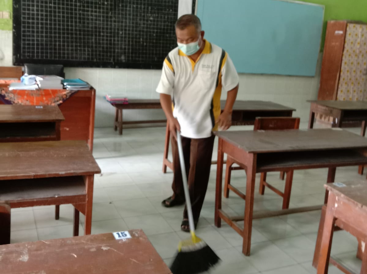 Seorang tenaga pendidik di salah satu SD Kota Mojokerto membersihkan ruang kelas dan mengecek sarpras jelang kegiatan PTM secara penuh mulai Senin (3/1/2021). /Foto: Susan