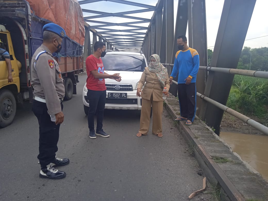Sri Wahyuliati Ningsih (42), guru SD memberi keterangan kepada polisi di atas jembatan Desa Tanjangrono, Kecamatan Ngoro, Senin (21/2/2022)./ Foto: Susan